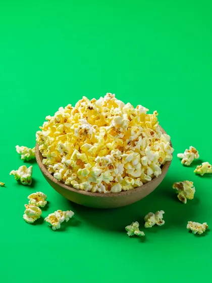 A bowl of popcorn shot for Bistro by Blinkit. The bright green background and clean lighting create a simple, graphic image ideal for online menus and promotional banners.