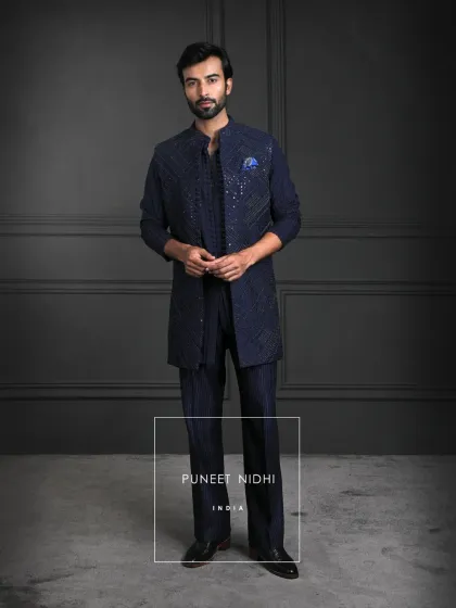 Between heritage and modernity lies this ensemble. A deep navy open jacket woven with geometric artistry, a sleek loop-buttoned tunic, and textured bell-bottom lowers.