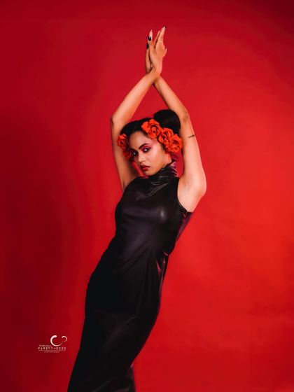 A powerful and expressive pose with arms raised. The floral hairpiece becomes a central focus, adding a touch of surreal beauty.