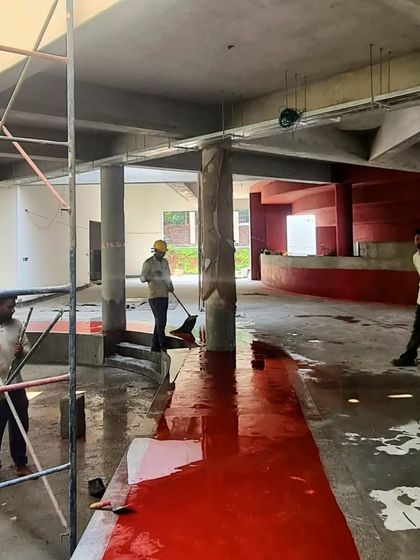 The site of the TAPMI Centre during the flooring process, showing the methodical craft required to achieve the seamless red oxide finish.