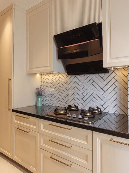 A closer view of the cooking area in a classic kitchen. This image shows the detailed cabinet profiles, sleek brass handles, and a striking herringbone tile backsplash that adds texture and character.