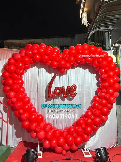A massive heart-shaped arch made entirely of red balloons. With a "Love" foil balloon in the center, this backdrop is a bold and romantic statement for any celebration of love.