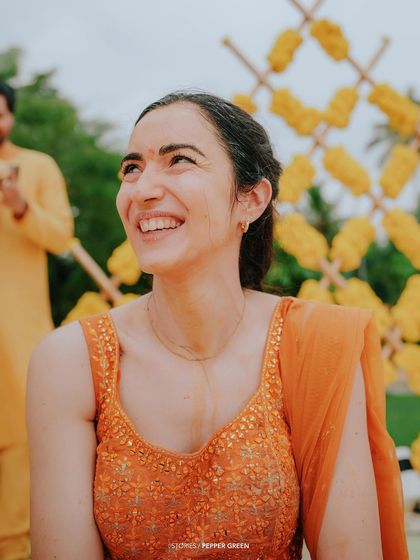 The bride, Eli, with a radiant smile during her Haldi ceremony. The bright, festive colors of the event make for visually stunning footage.