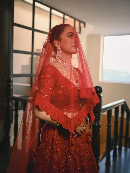 A portrait of the bride under her veil, looking thoughtfully into the distance. The soft light from the window creates a dreamy and ethereal mood.