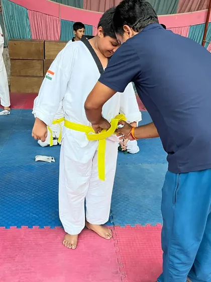 Adjusting the new yellow belt for a beginner. Each belt is a symbol of hard work and dedication.