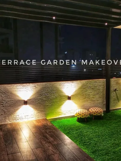 This cozy balcony corner uses a combination of dark wood decking and bright green artificial grass. The wall-mounted lights create a warm and inviting ambiance, perfect for a small, intimate setting.