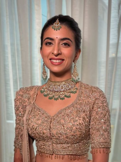 A beautiful, happy bride in a peach-golden lehenga. The makeup is kept soft and natural to let her joy shine through.