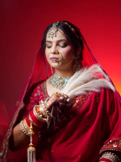 A serene bridal portrait against a rich red background. The soft lighting and her calm expression create a very peaceful and elegant image.