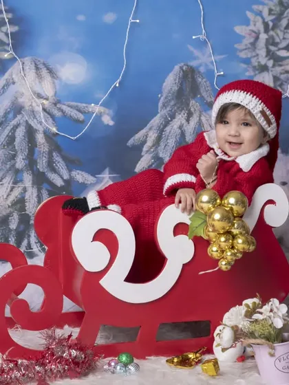 A happy baby Santa enjoying a sleigh ride in my winter wonderland studio setup. The twinkling lights and snowy backdrop make this a truly festive portrait.