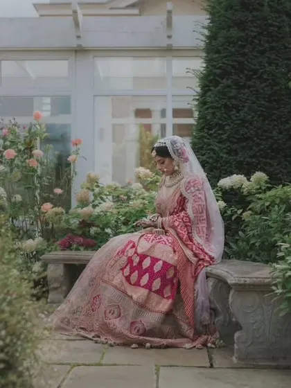 A serene bridal portrait in a beautiful English garden. The bride, in her traditional attire, looks peaceful and elegant amidst the lush greenery.