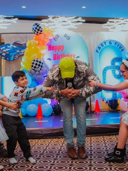 An anchor leading a fun group game of tug-of-war at a Hot Wheels themed party. They are masters of ceremonies, ensuring the party flows smoothly.