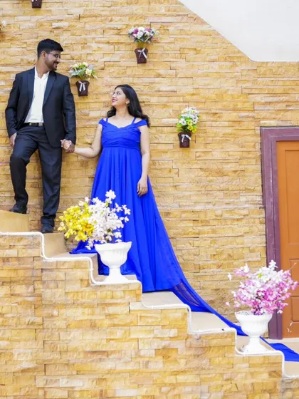 A grand entrance on a staircase decorated with flowers. The bride's royal blue gown with a long trail makes for a dramatic and beautiful pre-wedding picture.