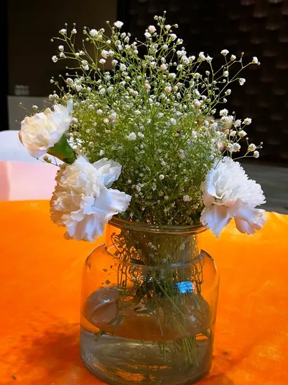 A simple and delicate centerpiece with baby's breath and white carnations in a clear glass jar.