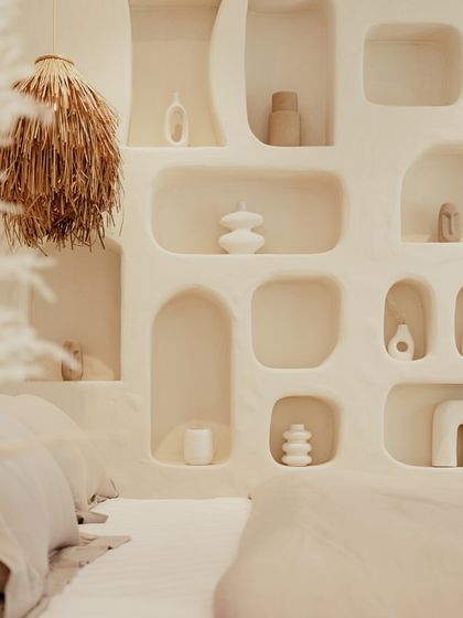 A close-up of the bedroom's feature wall reveals the soft, organic shapes of the built-in niches. These are perfect for displaying minimalist ceramic art, adding a personal and sculptural touch to the serene space.