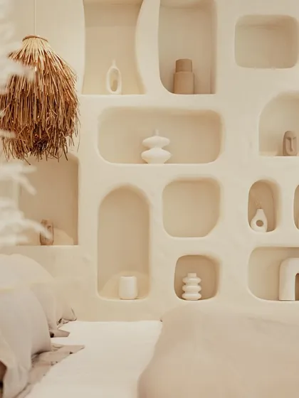 A close-up of the sculptural wall niches in the bedroom, filled with curated ceramic art pieces that add a personal and artistic touch to the serene space.