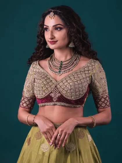 A close-up of the heavily embroidered blouse of the Banarasi lehenga. The detailed jaal pattern and contrasting velvet panel are clearly visible.