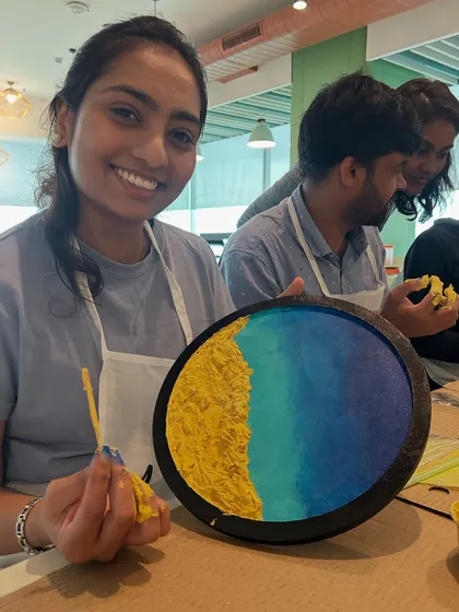 A participant from the Samsara tech workshop smiling with her completed resin beach art. We love seeing the pride and joy on people's faces.