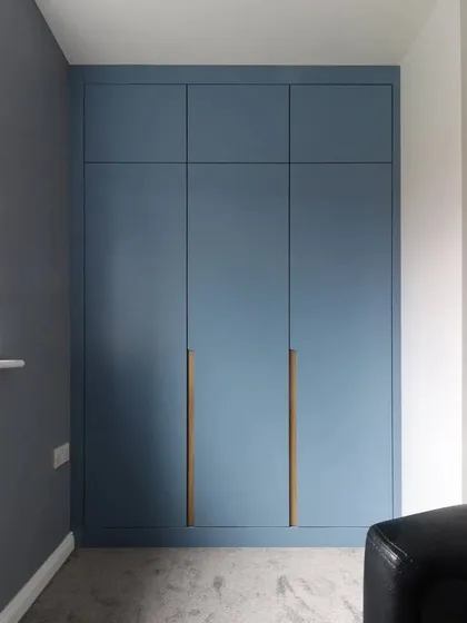 The same blue wardrobe shown with the doors closed, presenting a clean, seamless, and minimalist look.