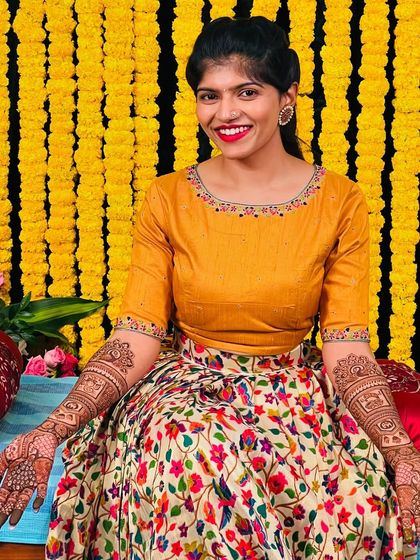 The beautiful bride Sahana, looking stunning in her floral lehenga, her hands open to show the intricate mehendi.