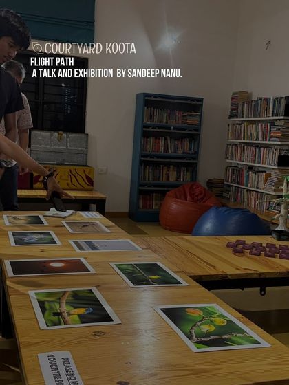 The "Flight Path" photo exhibition by Sandeep Nanu, showcasing his visual story of five years of birding. The photos are laid out on tables for an intimate viewing experience.