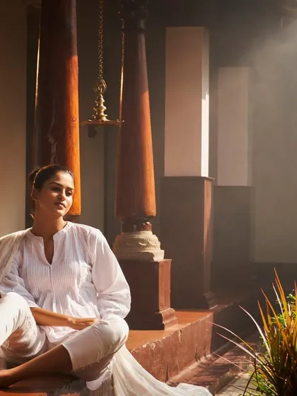 This is the feeling of post-treatment bliss. Here, a guest soaks in the serene, misty atmosphere of our heritage verandah after a rejuvenating Ayurvedic therapy session. This moment of quiet reflection is an essential part of the healing process, allowing the body and mind to absorb the benefits of the treatment.