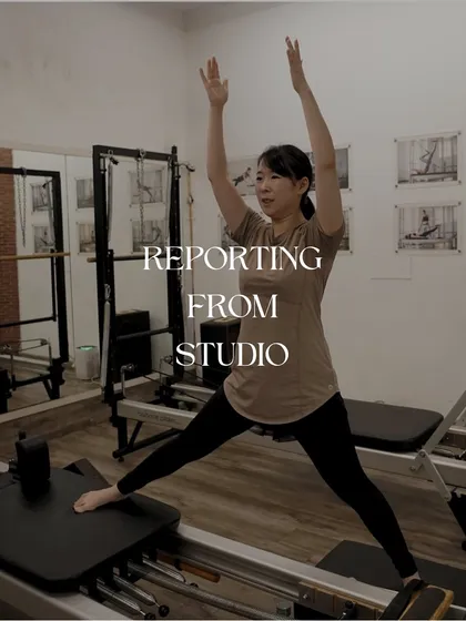 Reporting from the studio: a client performs a standing stretch on the reformer, showcasing balance and flexibility.