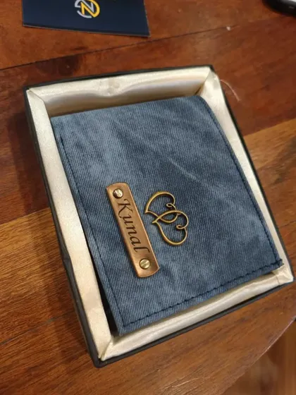 A personalized denim wallet in a stylish grey-blue, featuring a double heart charm and the name 'Kunal', presented in its gift box.