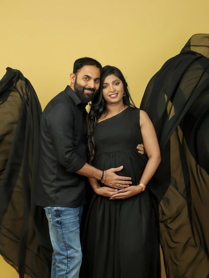 A classic couple's portrait in our studio. The father-to-be lovingly holds his partner's baby bump, showcasing their shared joy and anticipation.