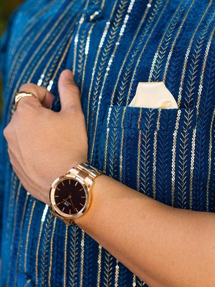 A close-up of the royal blue Nehru jacket, showing the texture of the sequined stripes and the elegant pocket square.
