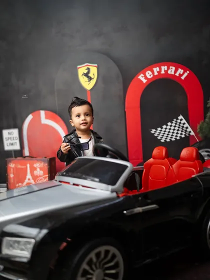 Standing tall next to his ride, this one-year-old is the star of his own race track. The leather jacket and slicked-back hair complete the look.