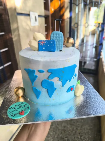 A bon voyage cake for a travel enthusiast. This design features a world map, fondant suitcases, and an Australian flag to celebrate an exciting journey ahead.
