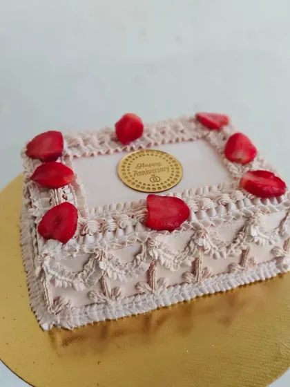 The full view of the square vintage anniversary cake, showing the intricate lace-like piping on the sides.
