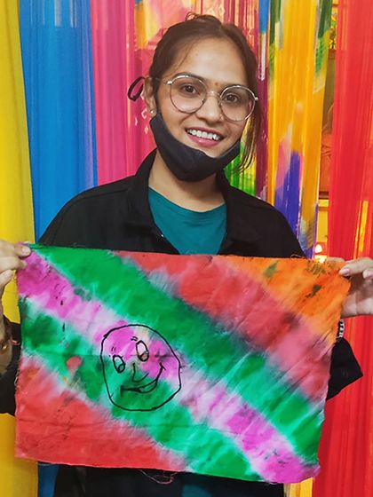 A student smiling with her colorful fluid art creation. Fluid art is a fun, expressive technique that is perfect for beginners and those looking to experiment with color.
