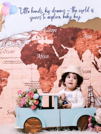 The world is yours to explore. This creative setup features a baby boy in a toy car in front of a world map, sparking dreams of future adventures.