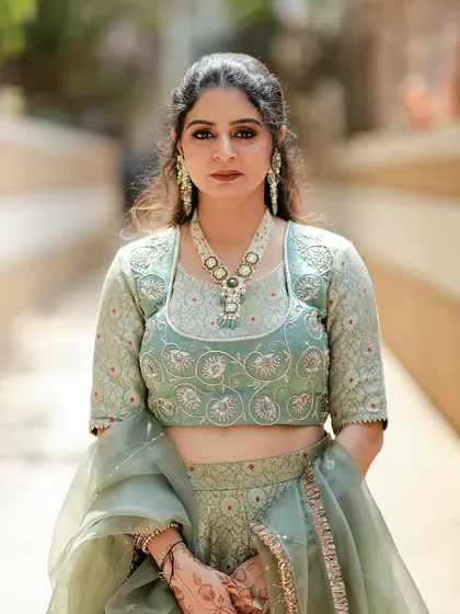 A direct, poised shot of our client in the pastel green brocade lehenga. Her elegant jewelry Fernsehserie complements the outfit's intricate embroidery and soft color palette.