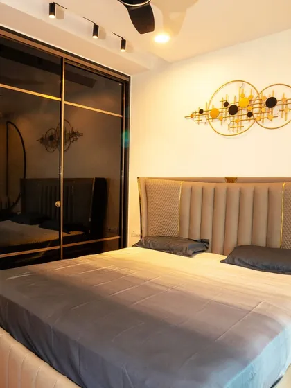The master bedroom at Brigade Cornerstone Utopia, featuring a sophisticated leatherette bed and a sleek Aristo wardrobe with black glass and gold profiles.