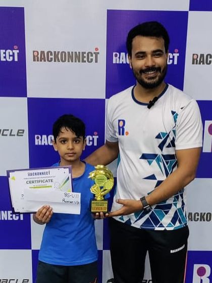 A proud moment for another young champion from my academy, posing with his coach and trophy after a successful tournament.