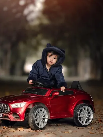A little explorer ready for a forest adventure in his red toy SUV. The moody lighting and natural setting create a dramatic and beautiful portrait.