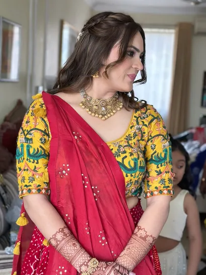 A beautiful, traditional look for a daytime ceremony. The client's vibrant red and yellow outfit is paired with soft, natural makeup and a half-up braided hairstyle for a touch of elegance.