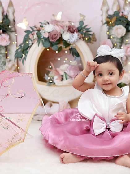 A classic, elegant portrait with a vintage touch. The pink parasol and floral arrangement add a timeless feel to this beautiful photo.