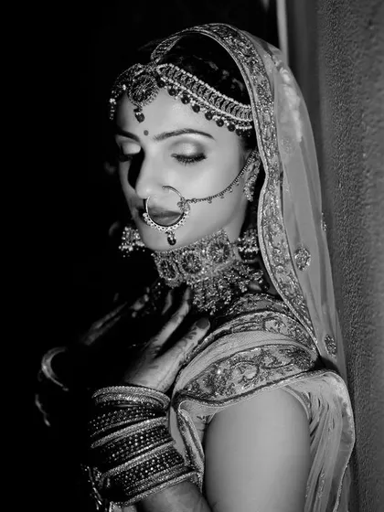 A timeless black and white portrait of a bride in a moment of quiet reflection. The dramatic lighting emphasizes her classic beauty and emotion.