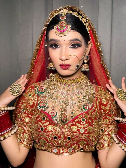 A stunning portrait of a bride in her red lehenga, looking directly at the camera with confidence.