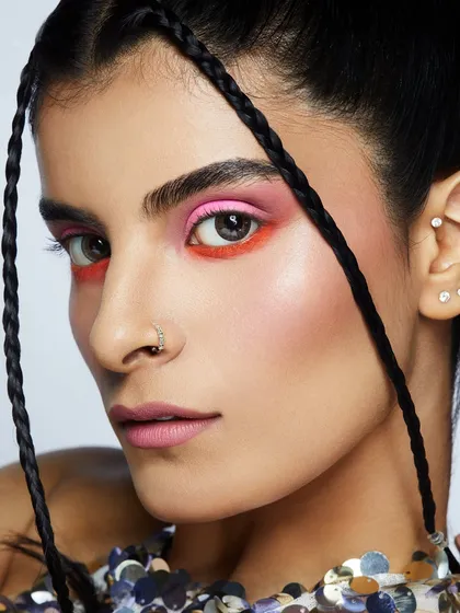 A vibrant, dual-toned eyeshadow look in pink and orange, paired with braids for a fresh and youthful feel.