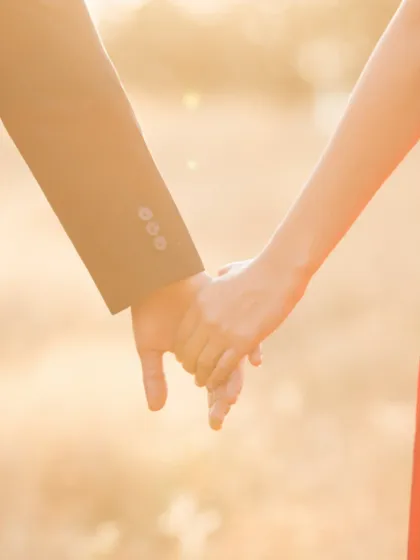 A close-up of the couple holding hands, bathed in warm, golden light. This shot symbolizes their connection and journey forward together.