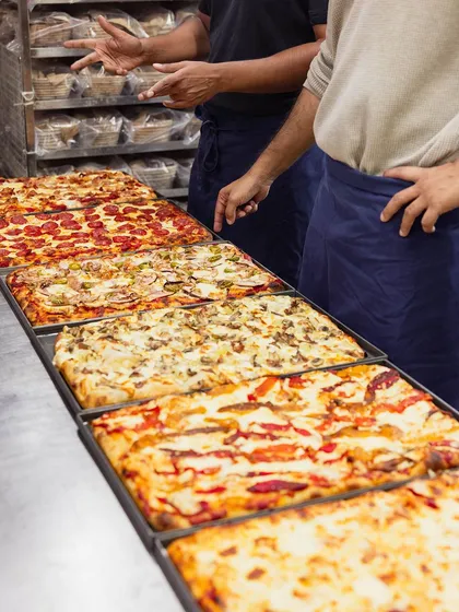 A lineup of our rectangular Pizza Romana trays, showcasing the variety of toppings available at our pop-up event.