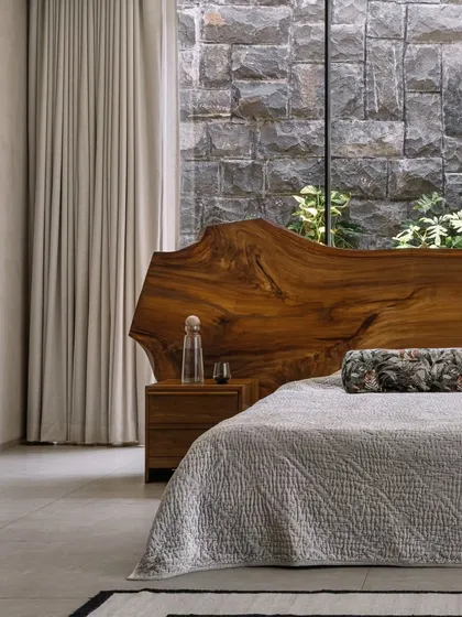 In our GAIA project in Chennai, we designed this master bedroom to be a serene retreat. The live-edge wood headboard brings a raw, natural element indoors, set against a rugged stone wall that connects the space to the earth, reflecting our modern organic and Wabi-Sabi design principles.