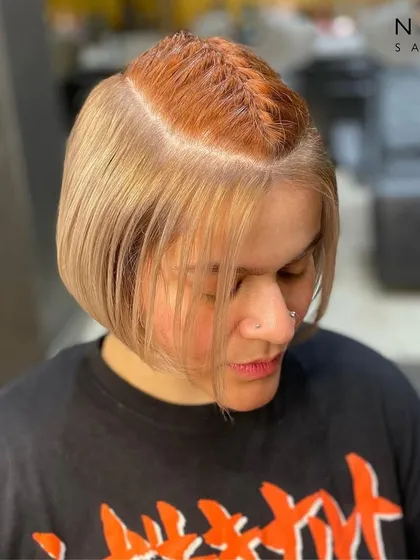 A playful peekaboo hair colour. This style features a bold orange braid hidden within a chic blonde bob, offering a fun surprise and a unique touch of personality.