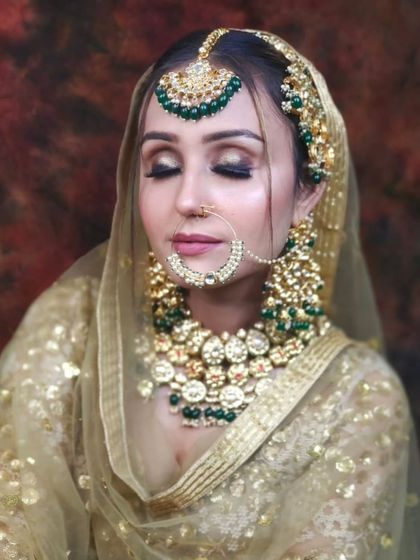 A bride in a golden sequined lehenga with a heavy green-beaded Kundan set. The contrast between the gold outfit and green jewellery is striking and beautiful.