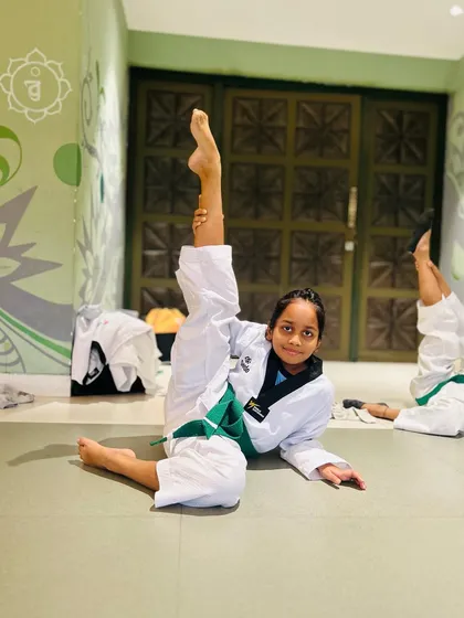 A student shows off her impressive flexibility with a split on the floor, a fundamental skill for any serious Taekwondo practitioner.