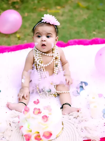 A look of surprise and delight during an outdoor cake smash. Her pearl necklaces and tutu add a touch of glamour to the messy fun.